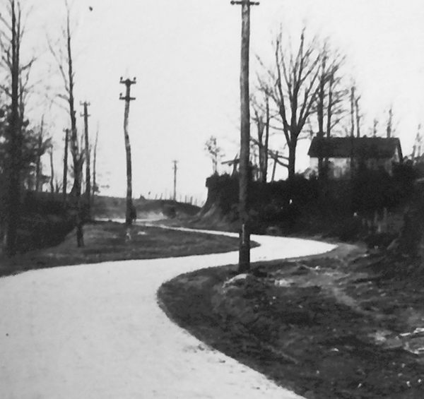 This black and white photograph, taken in 1918, depicts the Groveton School at the top of the hill on the right. The winding, curving road in the foreground is Route 1, which prior to straightening gave rise to this area being called Snake Hill.