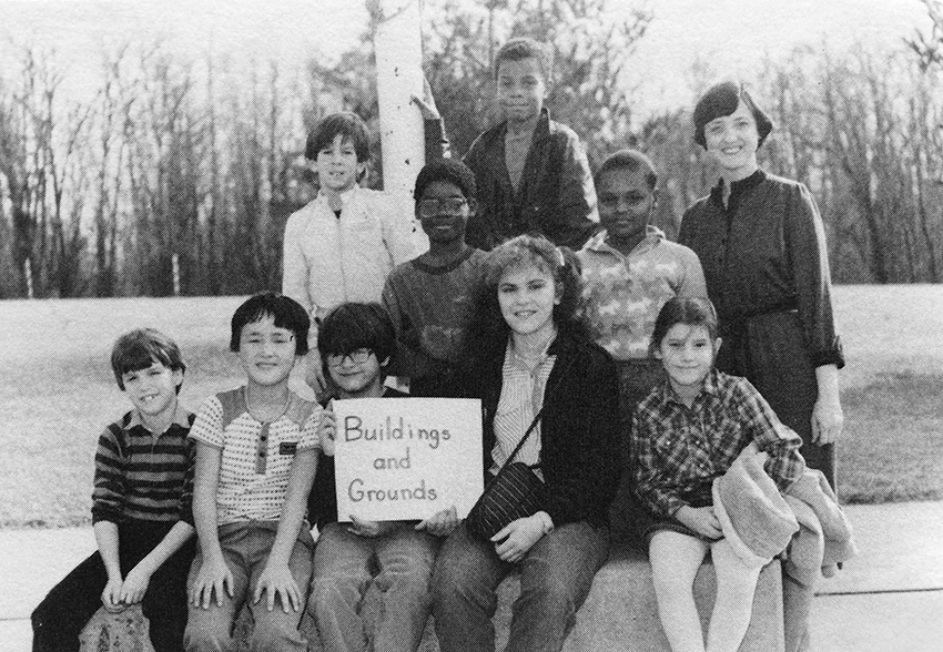 Black and white photograph of Groveton Elementary School's Building and Grounds Committee from the 1984 to 1985 yearbook. Eight children and two adults are pictured. They are seated outside next to the school's flagpole.